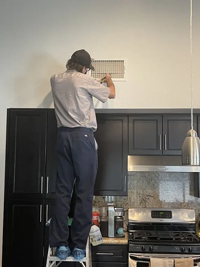 Technician inspecting an air vent during HVAC service in Stillwater